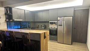 Eine moderne Küche mit grauen Schränken, einer Holztheke und einem eingebauten Backofen.