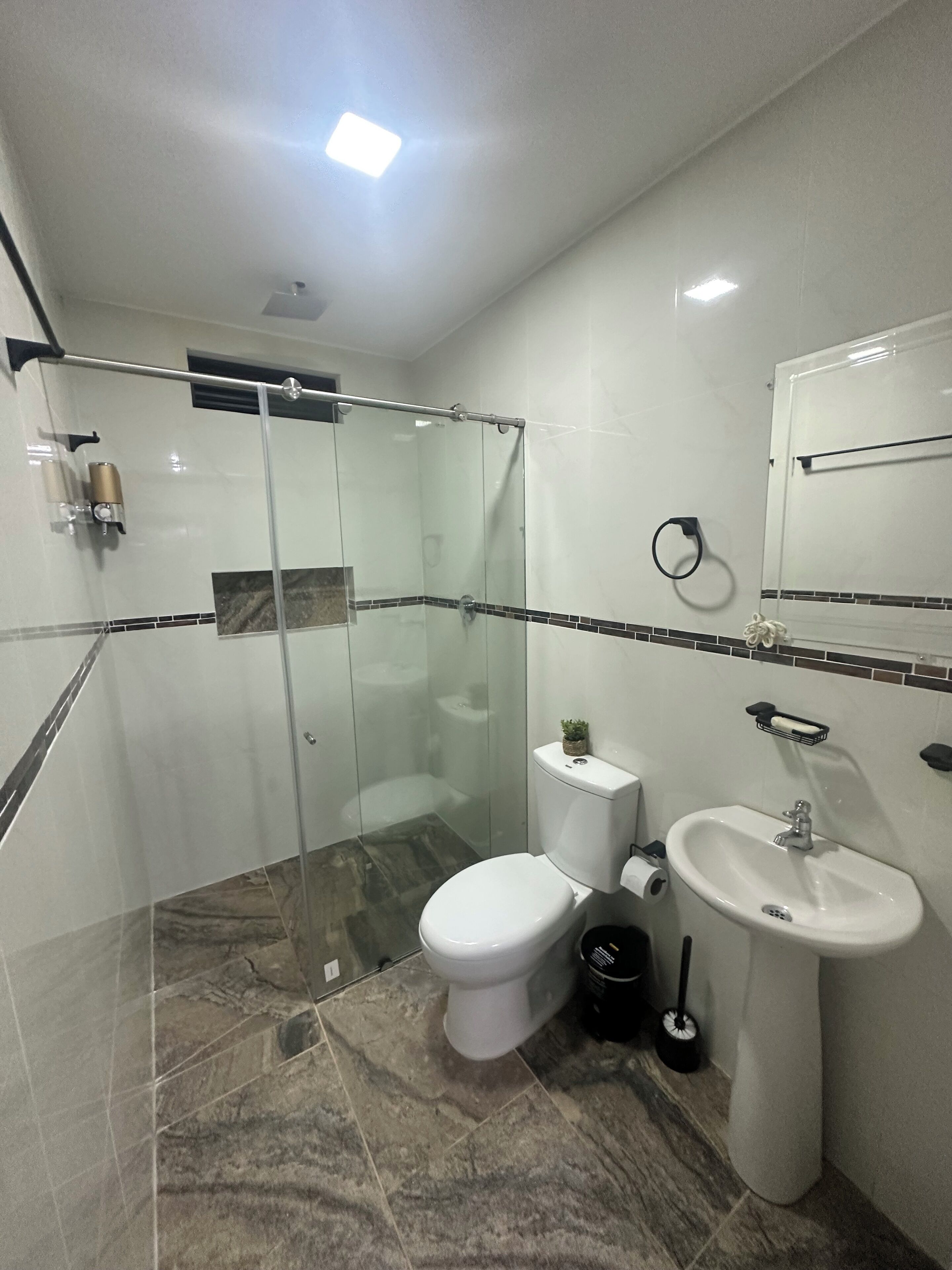 Ein modernes Badezimmer mit einer Duschkabine, Toilette, Waschbecken und Spiegel.