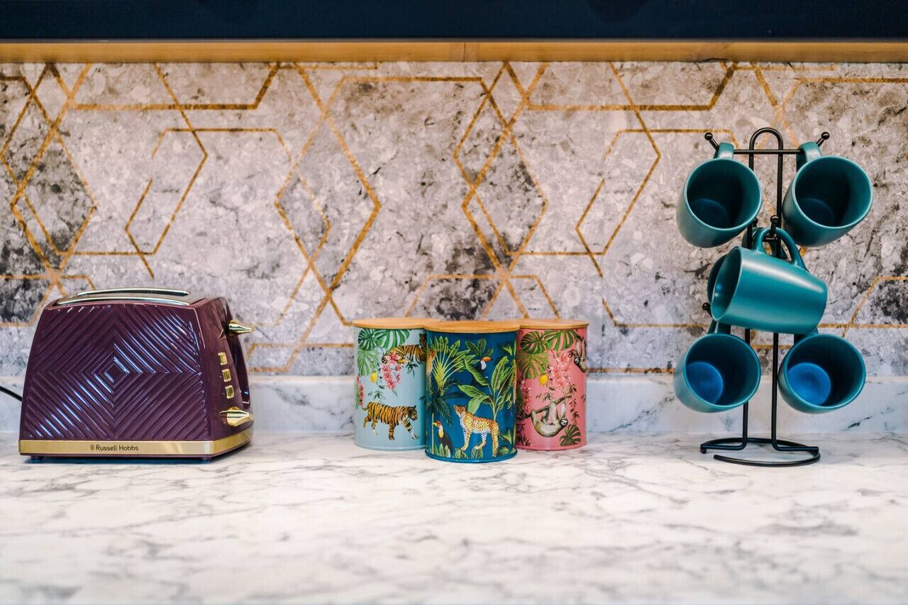 A kitchen with a marble countertop, a vintage radio, and three colorful coffee mugs.