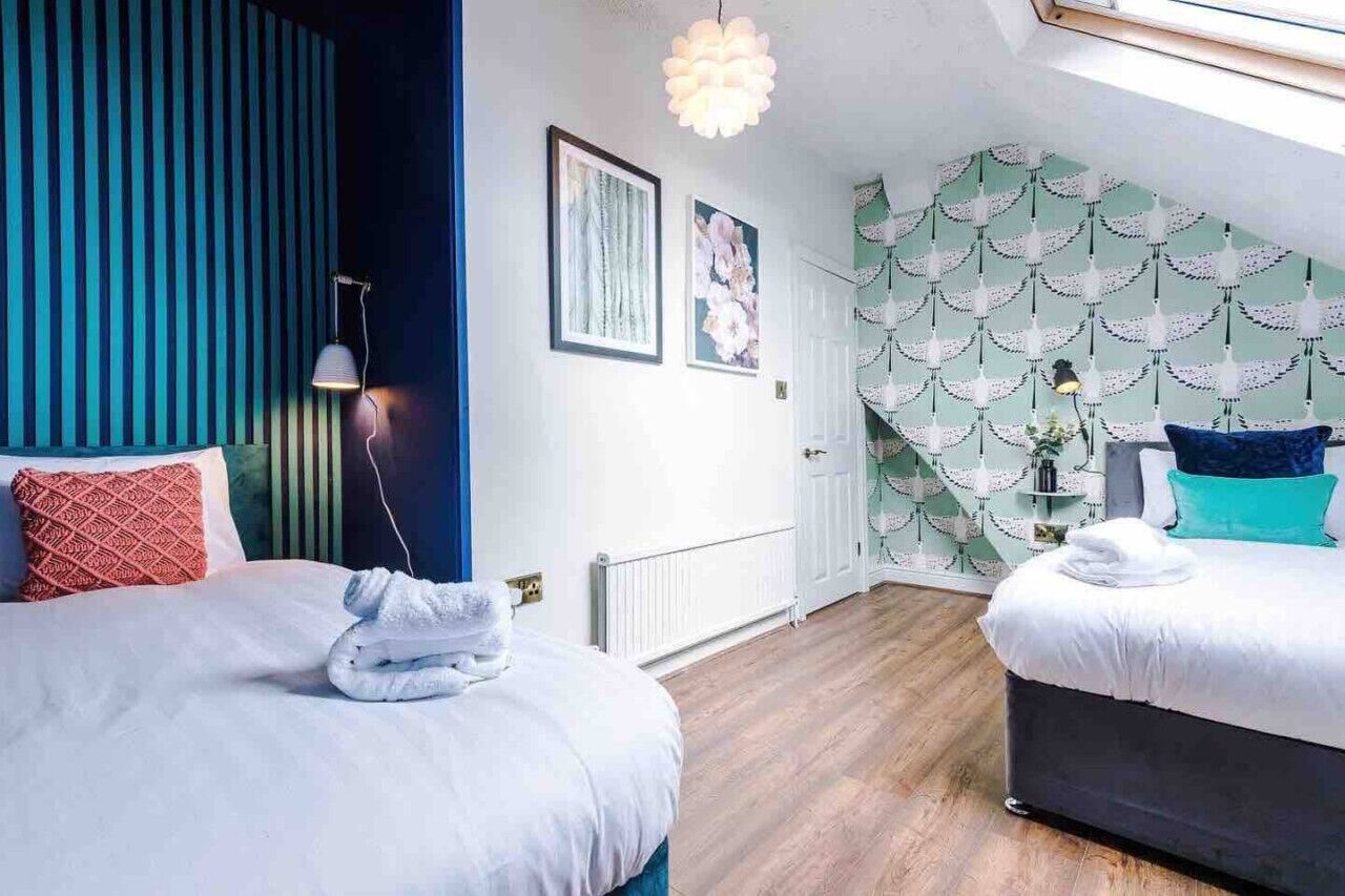 A hotel room with two beds, a large window, and a decorative wall pattern.