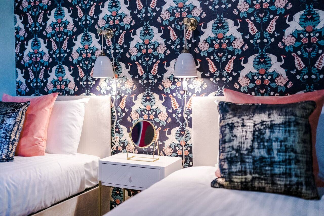 Una camera da letto con due letti, un comodino, uno specchio e applique.