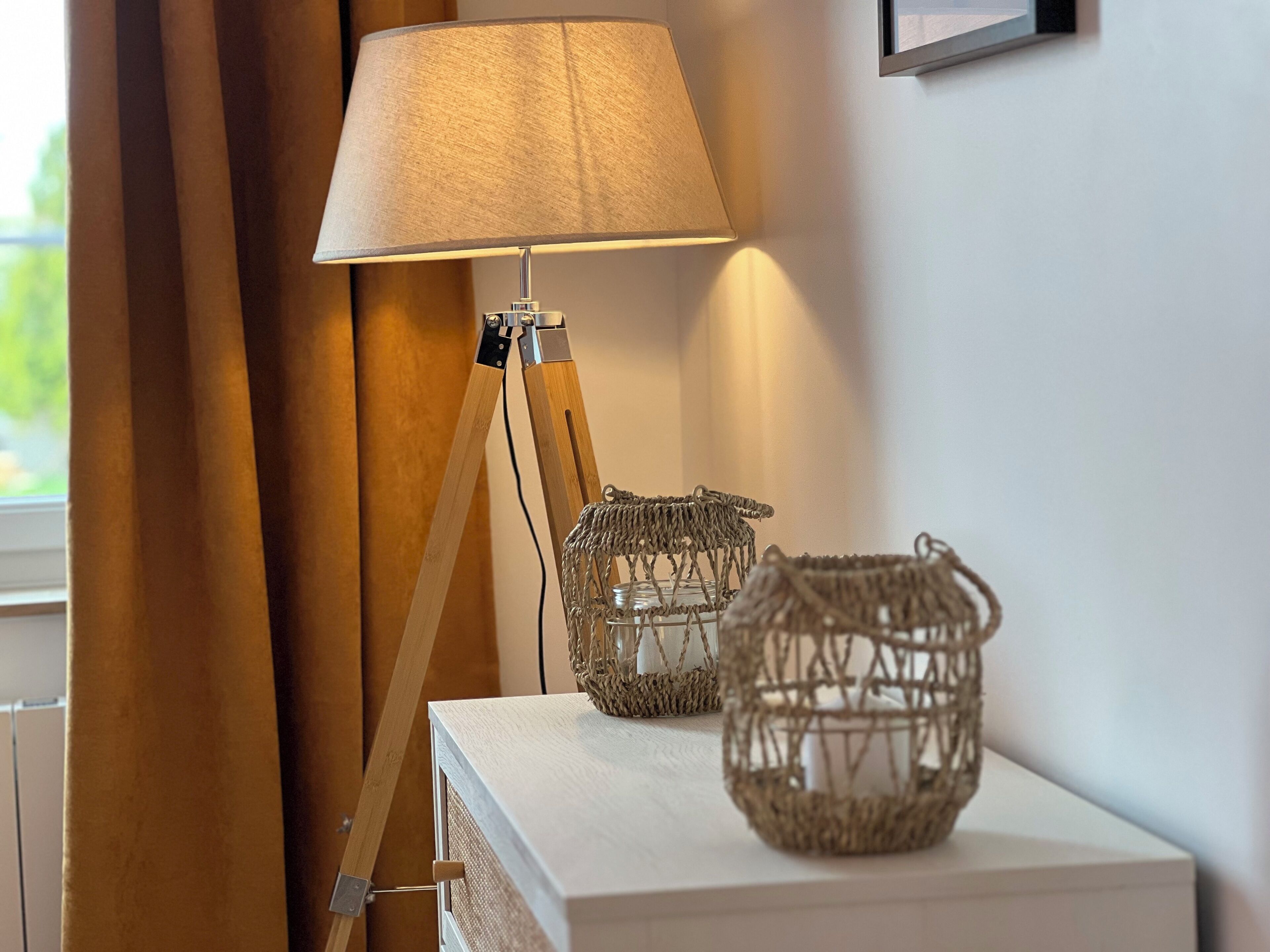 Une lampe avec un pied en bois et un abat-jour en tissu, posée sur une table blanche.