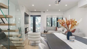 Ein modernes Wohnzimmer mit Glastreppe, Flachbildfernseher, einer Couch und einem Essbereich.