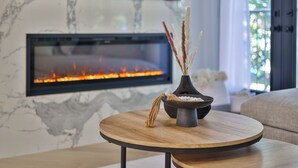 Ein modernes Wohnzimmer mit Kamin, einem runden Holztisch und einer Vase mit dekorativen Elementen.
