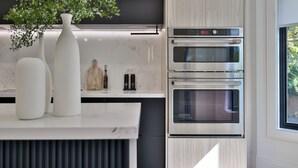 Eine moderne Küche mit integrierten Geräten, einer weißen Arbeitsplatte und einem Fenster mit Blick auf Grünflächen.