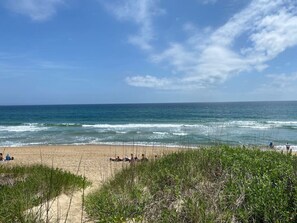 A beach with people relaxing and the ocean in the background.