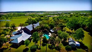 An aerial view of a residential area with multiple houses, a swimming pool, and surrounding greenery.