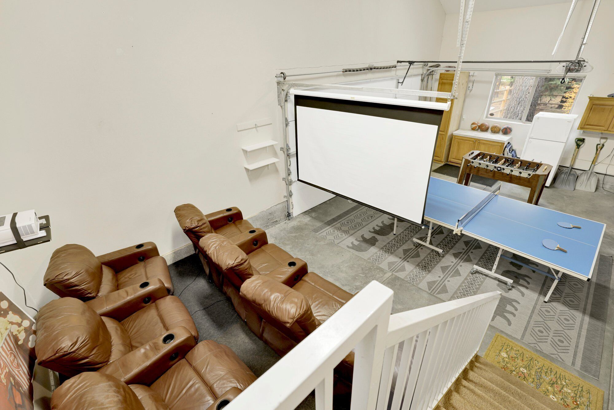 A room with a massage chair area, a foosball table, and a ping pong table.