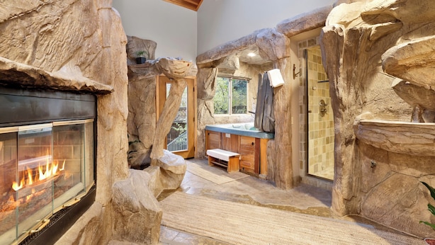 A stone-walled bathroom with a bathtub, shower, and a fireplace. - THE SPA AT Winterset #2282 (Big Bear Lake)