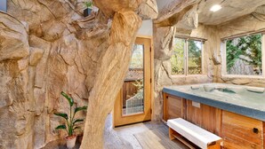 A spa area with a hot tub, wooden benches, and a rock wall. - THE SPA AT Winterset #2282 (Big Bear Lake)