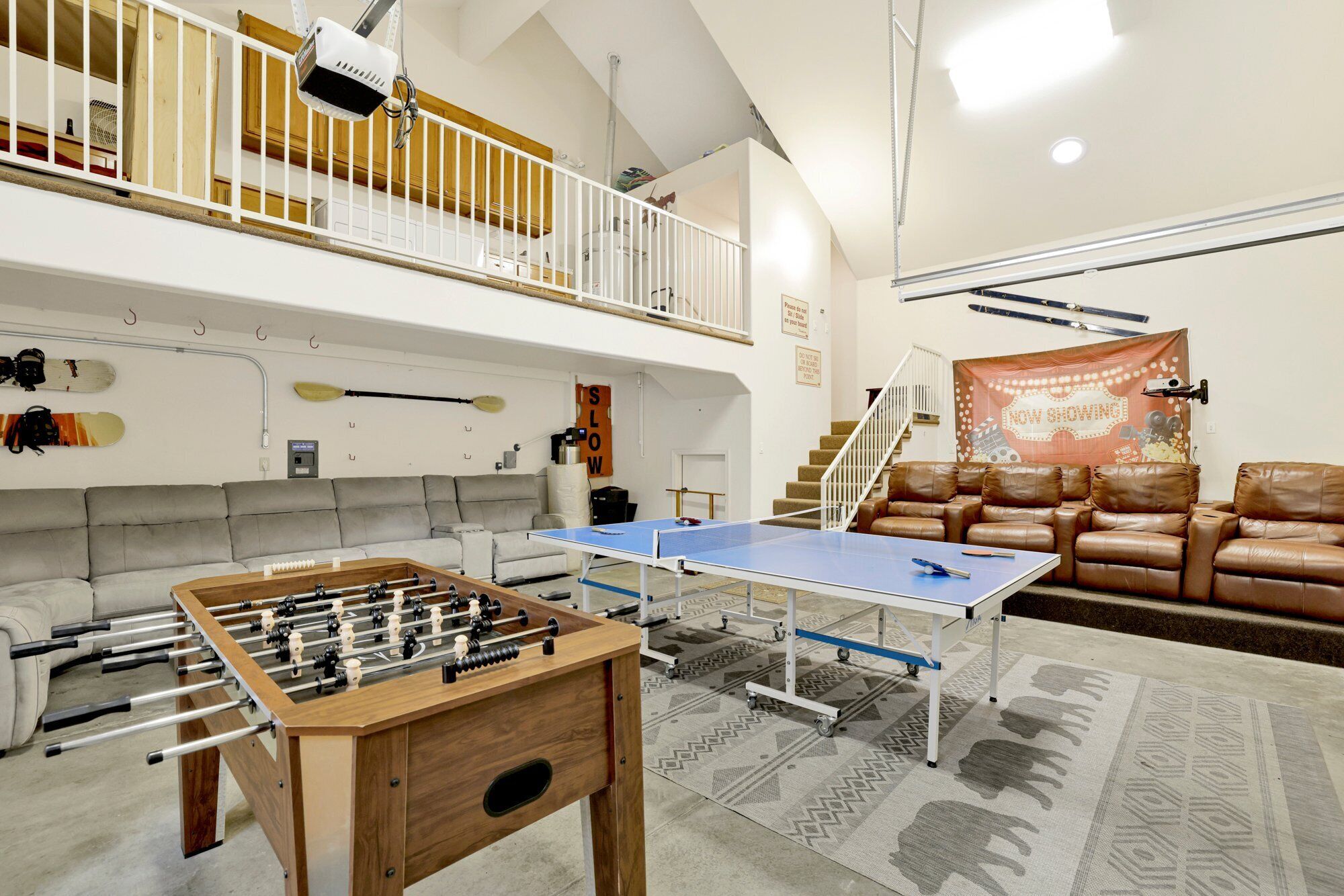 A spacious living area with a foosball table, ping pong table, and a couch.