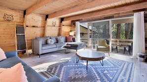 Un intérieur chaleureux avec des éléments en bois, un canapé gris, une petite table ronde et un tapis à motifs.