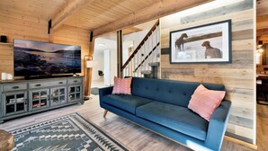 Un salon moderne avec un canapé bleu, un téléviseur et un escalier.