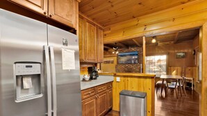 A kitchen with wooden cabinets, a stainless steel refrigerator, a water dispenser, and a trash can. - Silvertip Pines #2335 (Big Bear Lake)