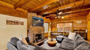 A cozy living room with a fireplace, a large sofa, and a dining area with a table and chairs. - Silvertip Pines #2335 (Big Bear Lake)