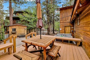 Eine Holzterrasse mit Picknicktischen und einem Whirlpool.