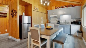 Une cuisine moderne avec des murs en bois, un réfrigérateur en acier inoxydable, une table à manger avec des chaises et un four à micro-ondes.