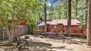 Un chalet rustique doté d’une terrasse en bois, entouré d’arbres.