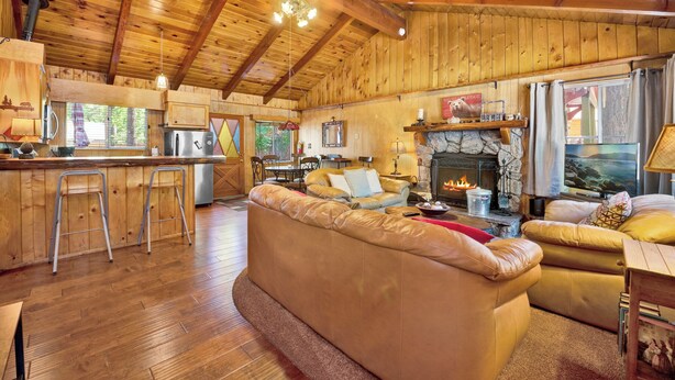 L’intérieur d’un chalet confortable, avec des murs en rondins de bois, une cheminée en pierre, des meubles en bois et un coin cuisine.