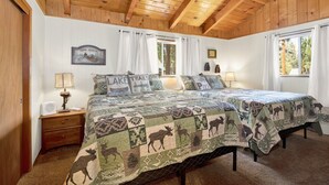 Une chambre confortable avec un plafond en bois, deux lits avec une literie à motifs, une table de chevet avec une lampe et une fenêtre avec des rideaux.