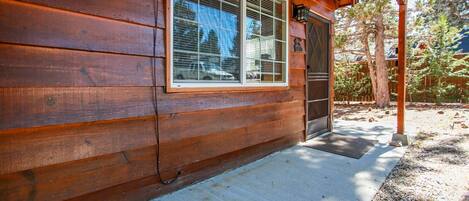 Una cabaña de madera con un ventanal grande, una puerta de garaje y un porche cubierto.