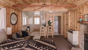 Een knus kamer in chaletstijl met een bed, een houten plafond, een open haard en een keukenhoek.