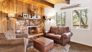 A cozy living room with a stone fireplace, leather furniture, and a 'Weekend Getaway!' sign. - Chipmunk Treehouse #1983 (Big Bear Lake)