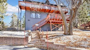 A two-story building with a wooden deck and a staircase leading to the upper level. - Chipmunk Treehouse #1983 (Big Bear Lake)