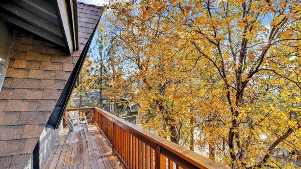 A wooden deck with a railing, overlooking a yard with autumn-colored trees. - Chipmunk Treehouse #1983 (Big Bear Lake)