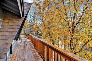 A wooden deck with a railing, overlooking a yard with autumn-colored trees. - Chipmunk Treehouse #1983 (Big Bear Lake)