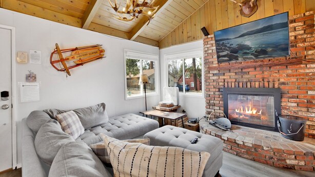 A cozy living room with a sectional sofa, a fireplace, and a mounted Western Clipper sign.