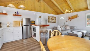 A cozy kitchen with wooden beams, a dining table, and a gray sofa.