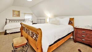 Un dormitorio con dos camas, un cabecero de madera, una mesita de noche, un aparador y un cuadro en la pared.