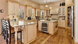 A spacious kitchen with wooden cabinets, a central island, and a refrigerator.