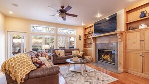 A spacious living room with a fireplace, wooden cabinets, and a large window.