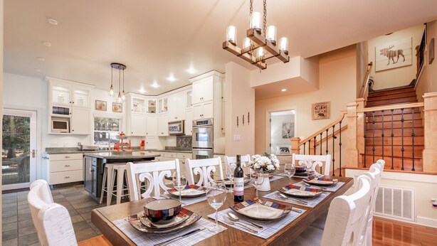 A spacious kitchen with white cabinets, a central island, and a dining area with a wooden table set for six.