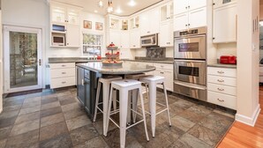 A modern kitchen with white cabinets, stainless steel appliances, and a central island with stools.