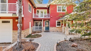 A two-story red house with a front porch, a garage, and a stone foundation.