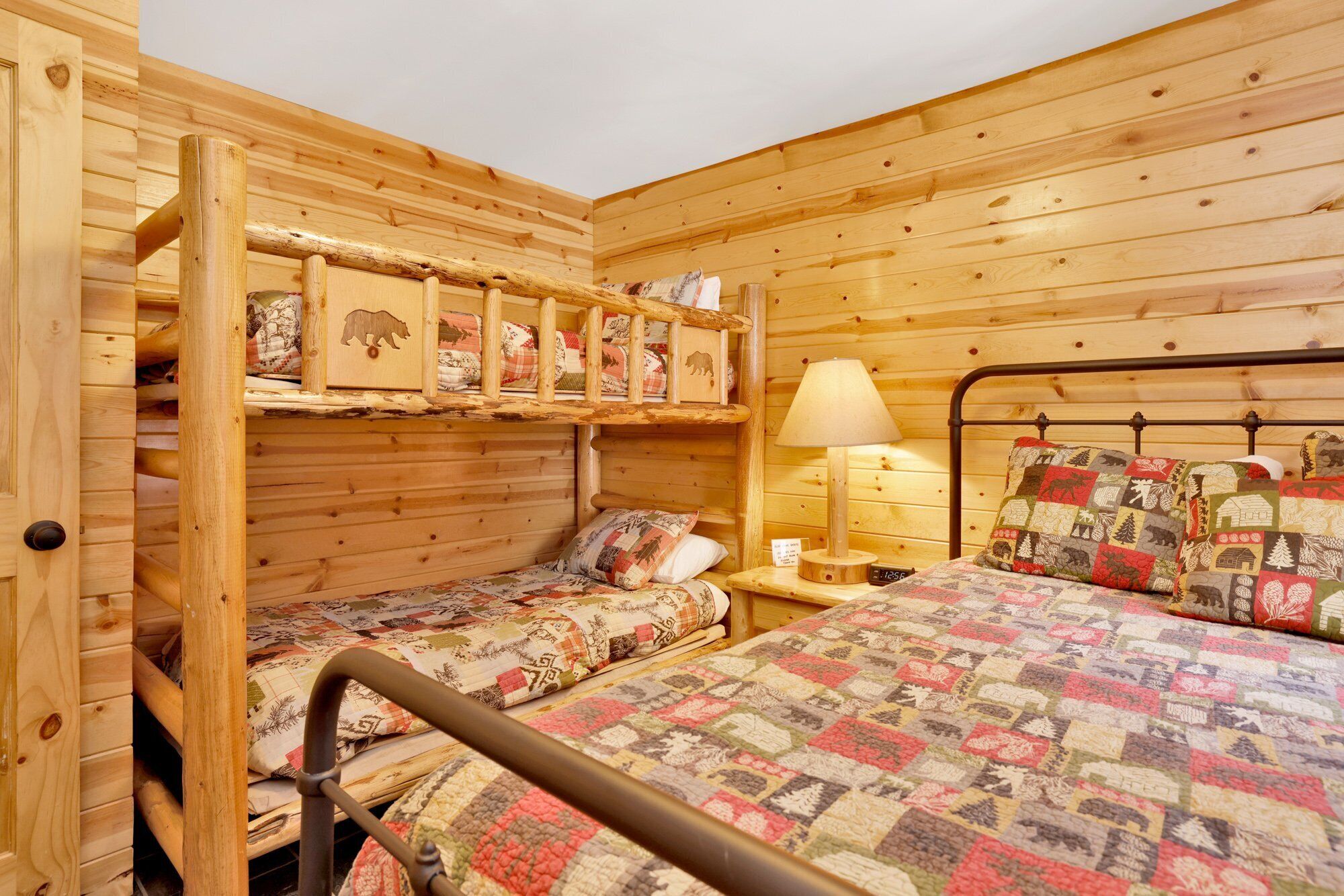 A cabin-style room with a bunk bed, a single bed, and a wooden headboard.