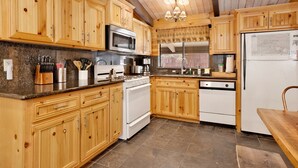 A kitchen with wooden cabinets, a microwave, stove, and a refrigerator.