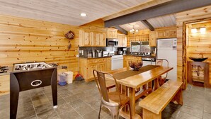 A cozy kitchen with wooden walls, a foosball table, and a dining area with a bench.