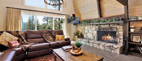 Una sala de estar acogedora con chimenea de piedra, sofá de cuero y mesa de centro de madera.