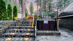 A set of stone steps leading to a spa entrance with a sign indicating spa hours. - Bears Palace Chalet #2008 (Big Bear Lake)