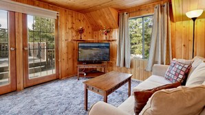 Un interior de madera con televisor, sofá y puerta al balcón.