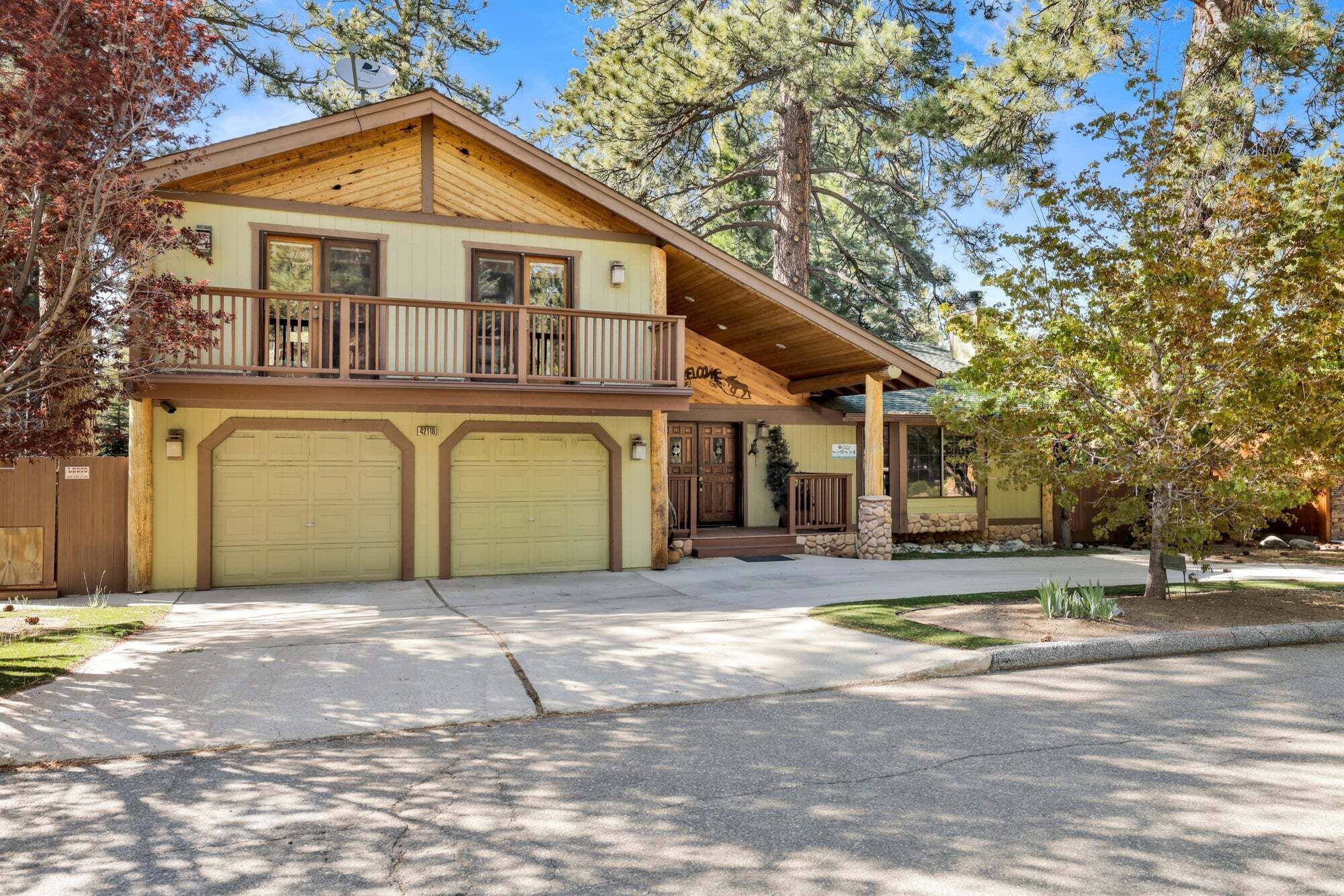 A two-story house with a balcony, a garage, and a stone foundation.