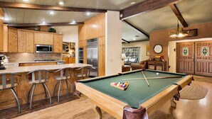 A pool table with a green felt surface, wooden pool cues, and a set of balls. - Moose Manor #2012 (Big Bear Lake)