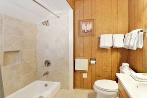 A bathroom with a bathtub, shower, toilet, and wooden paneling. - Pinglewood Cabin #2096 (Fawnskin)