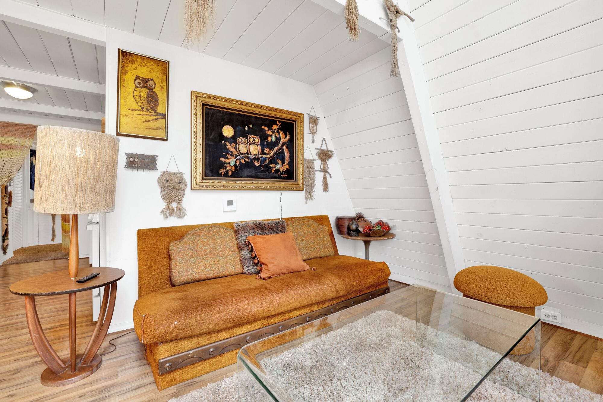 Una sala de estar acogedora con un sofá, una mesa de centro de vidrio y una lámpara.