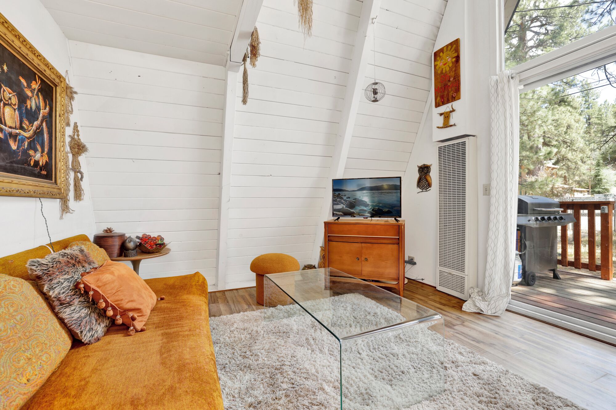Un salon chaleureux avec un canapé, une table basse en verre et un téléviseur posé sur un meuble en bois.