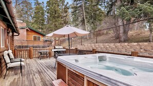 A wooden deck with a hot tub, picnic tables, and a barbecue grill. - Bear Tracks #2020 (Big Bear Lake)